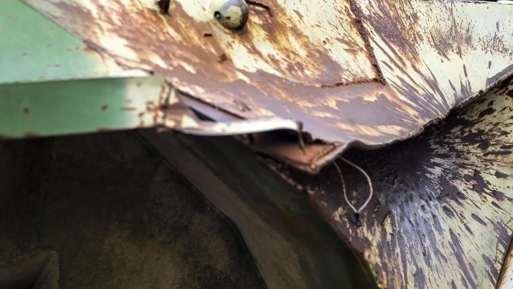 Hole or hole, armor deformation from a projectile close-up. Damaged armor of a Russian armored personnel carrier by shell fragments. War in Ukraine. Russian combat vehicle with holes in the armor. photo