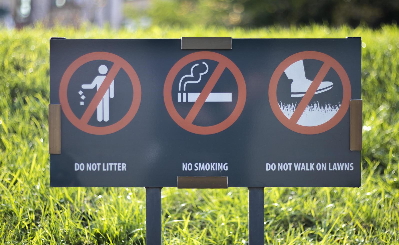 An information sign showing prohibition signs at the entrance to the park on a sunny summer day. Do not litter, do not smoke, do not walk on lawns. photo