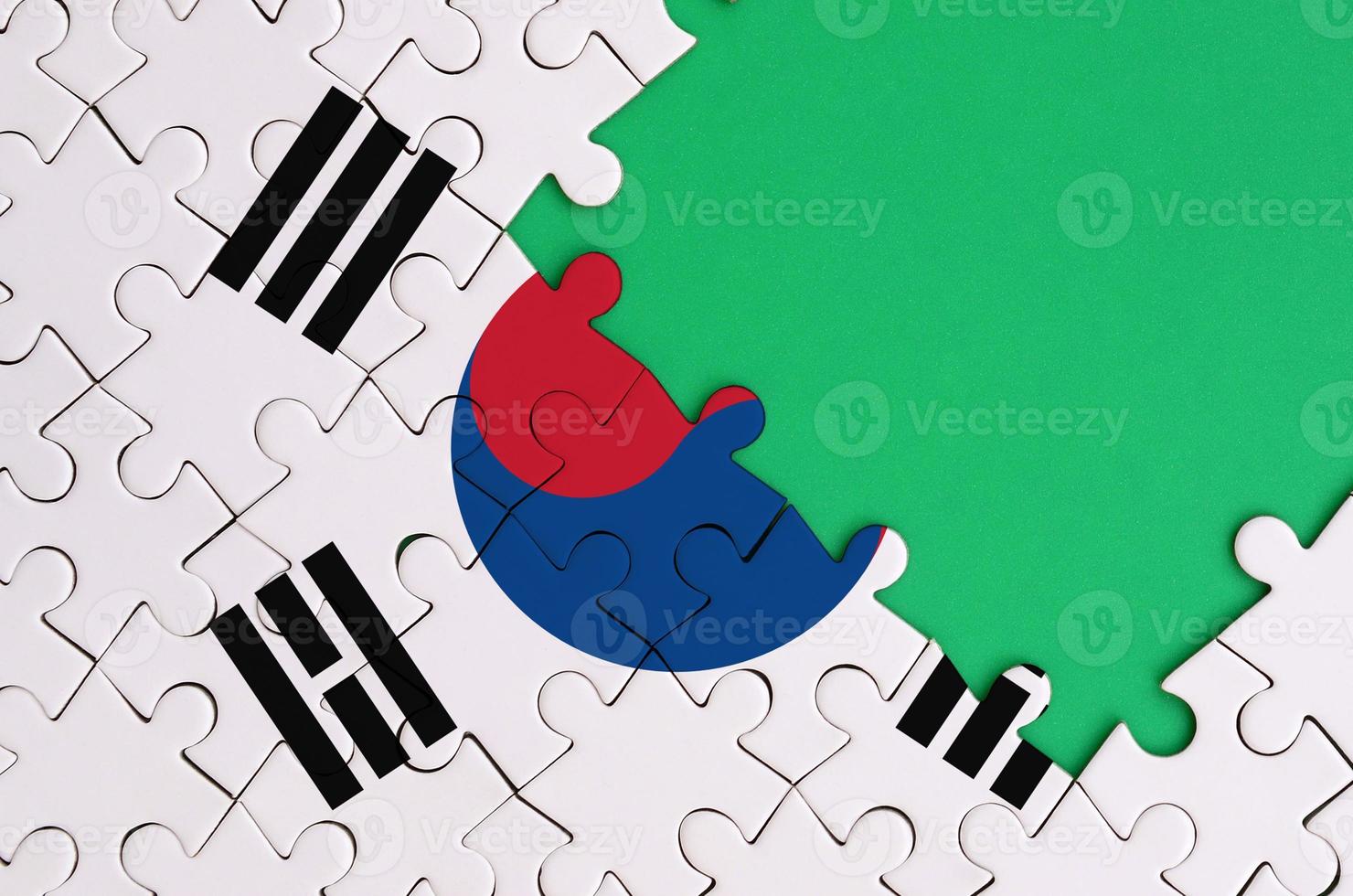 South Korea flag is depicted on a completed jigsaw puzzle with free green copy space on the right side photo