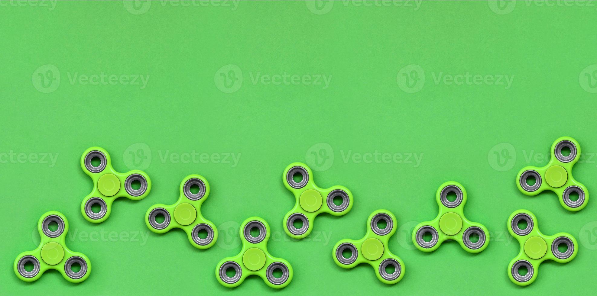 Many green fidget spinners lies on texture background of fashion pastel green color paper in minimal concept photo