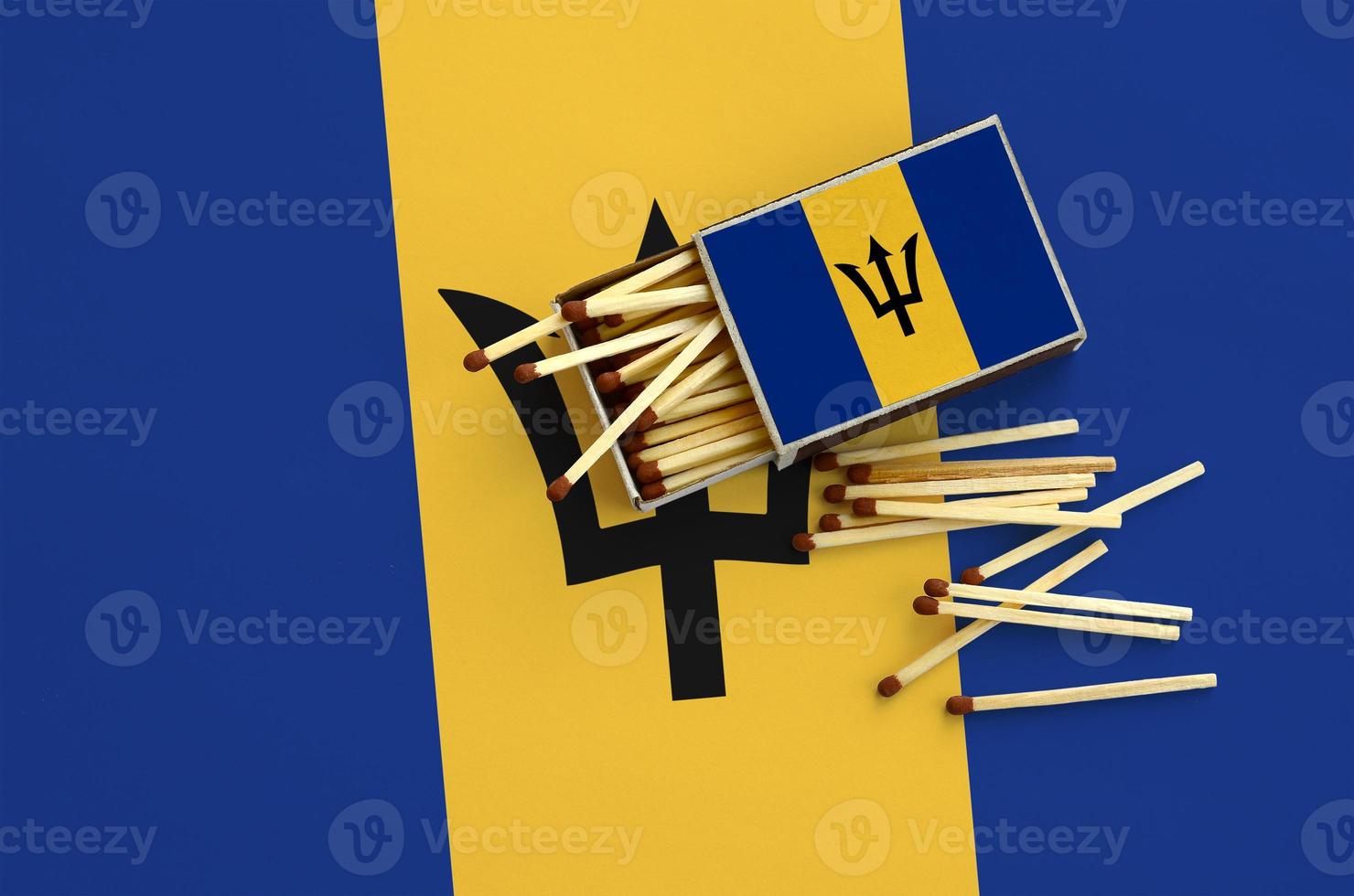 Barbados flag is shown on an open matchbox, from which several matches fall and lies on a large flag photo