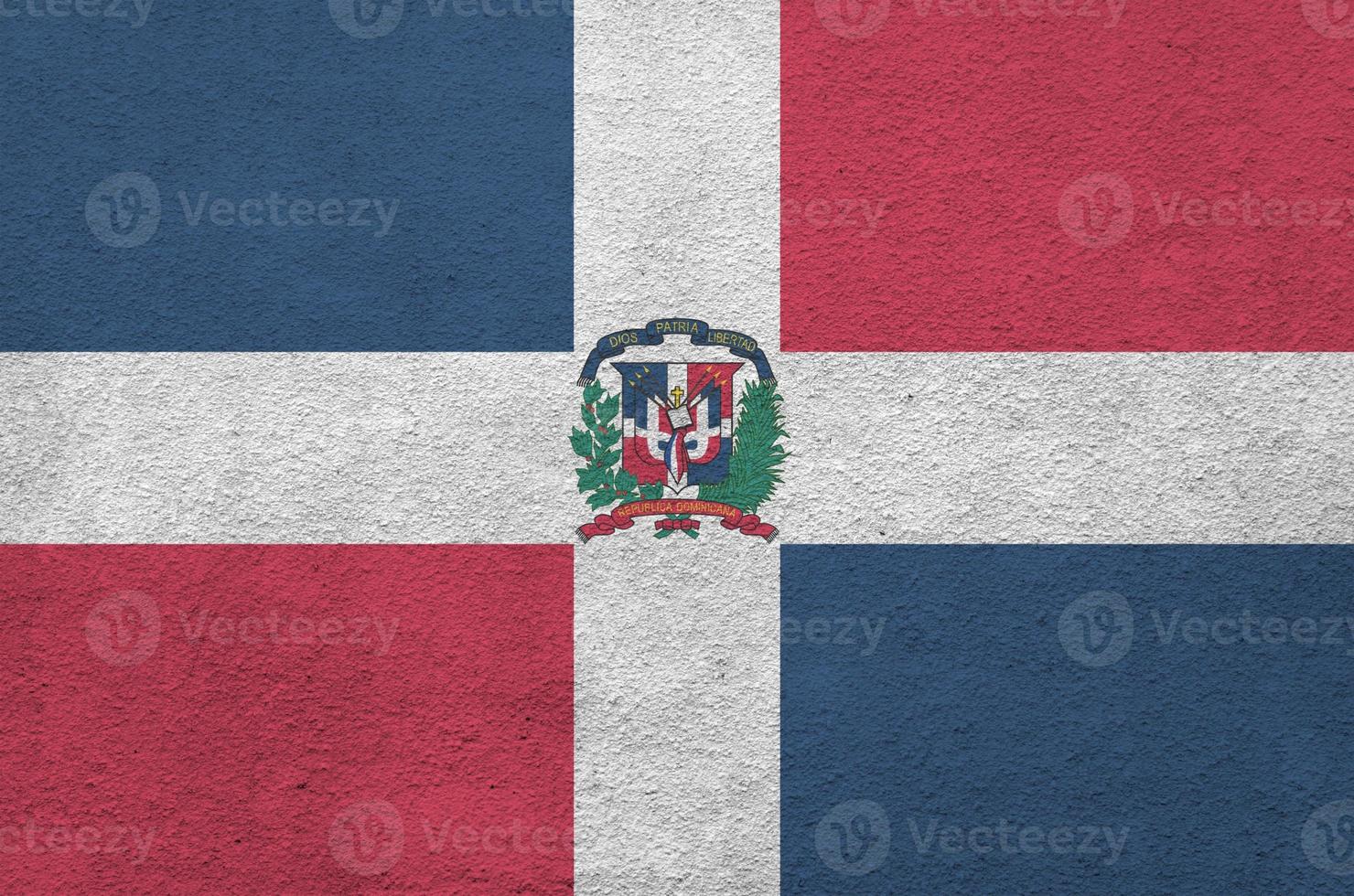 Dominican Republic flag depicted in bright paint colors on old relief plastering wall. Textured banner on rough background photo