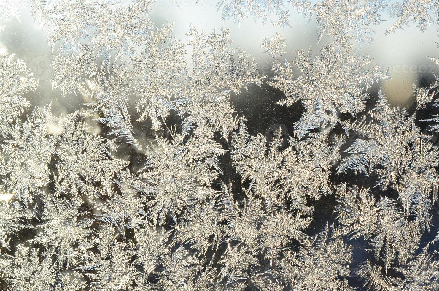 Snowflakes frost rime macro on window glass pane photo