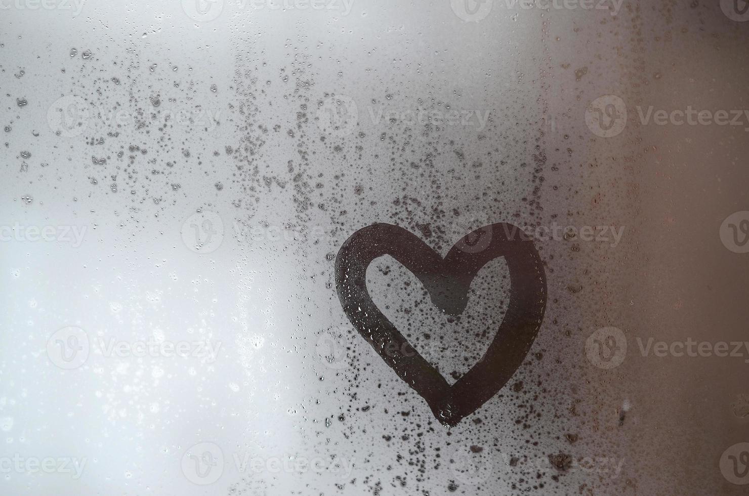 The heart is painted on the misted glass in winter photo