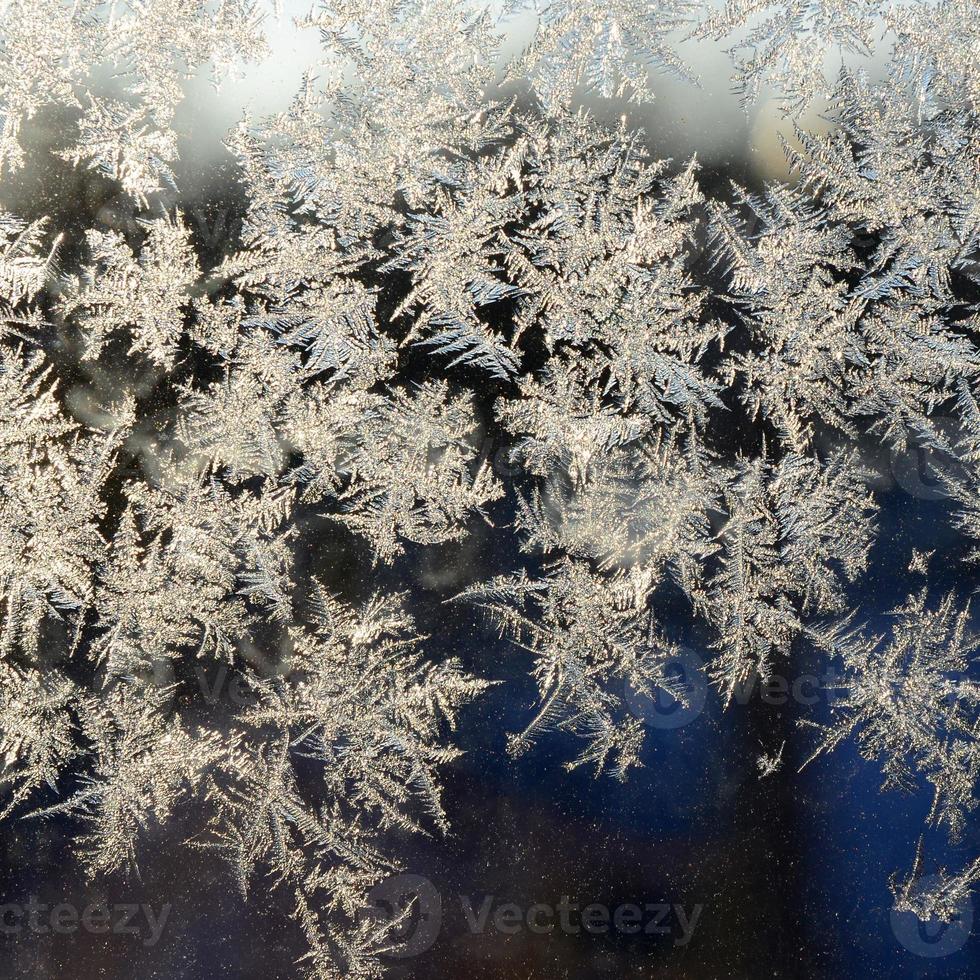 Snowflakes frost rime macro on window glass pane photo