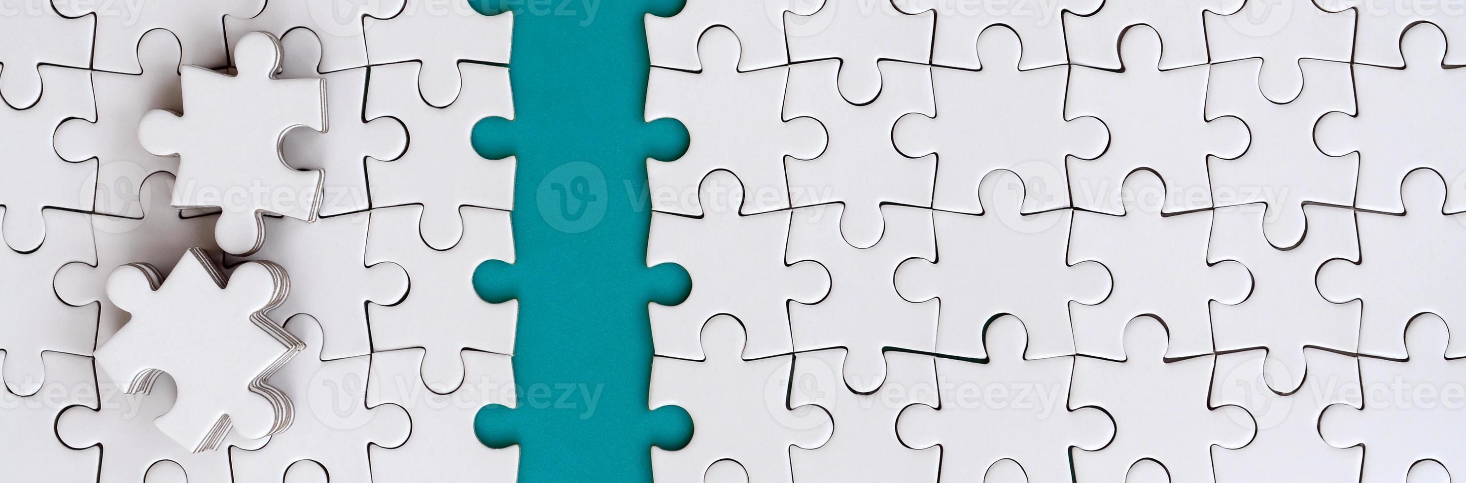 The blue path is laid on the platform of a white folded jigsaw puzzle. The missing elements of the puzzle are stacked nearby. Texture image with space for text photo
