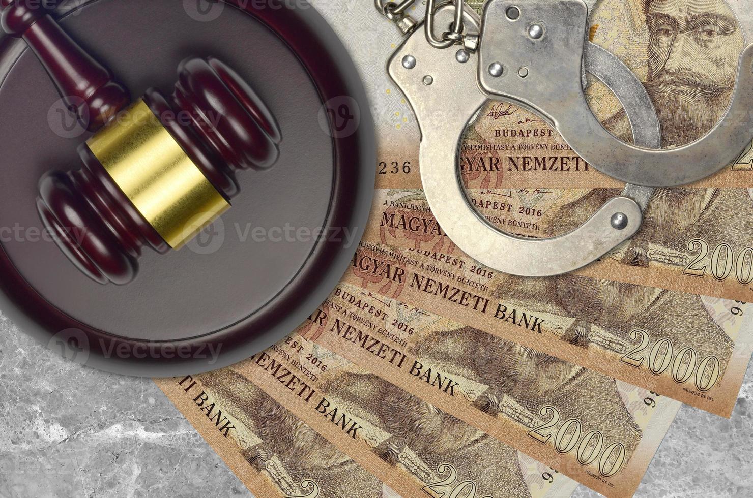 2000 Hungarian forint bills and judge hammer with police handcuffs on court desk. Concept of judicial trial or bribery. Tax avoidance photo