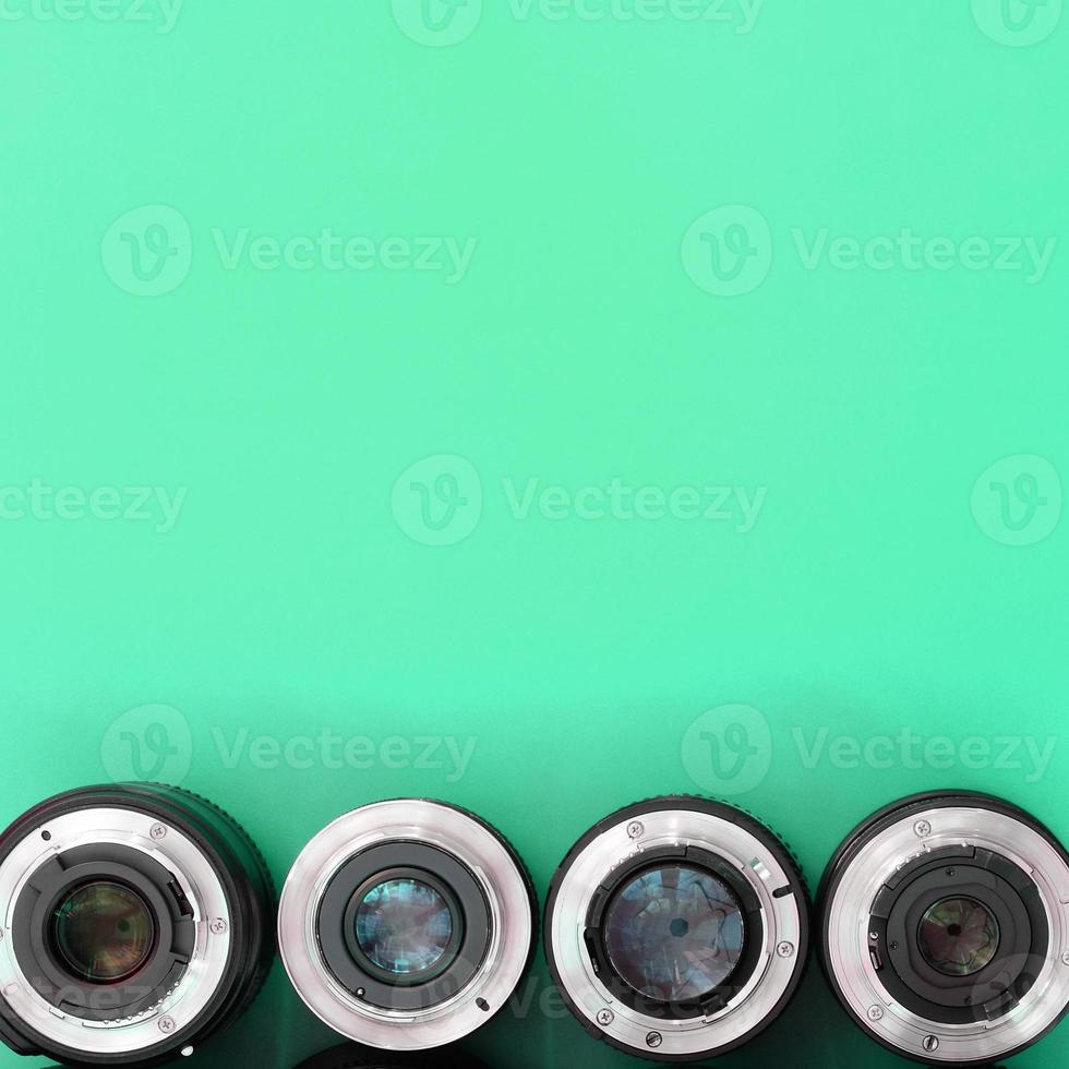 Several photographic lenses lie on a bright turquoise background. Copy space photo