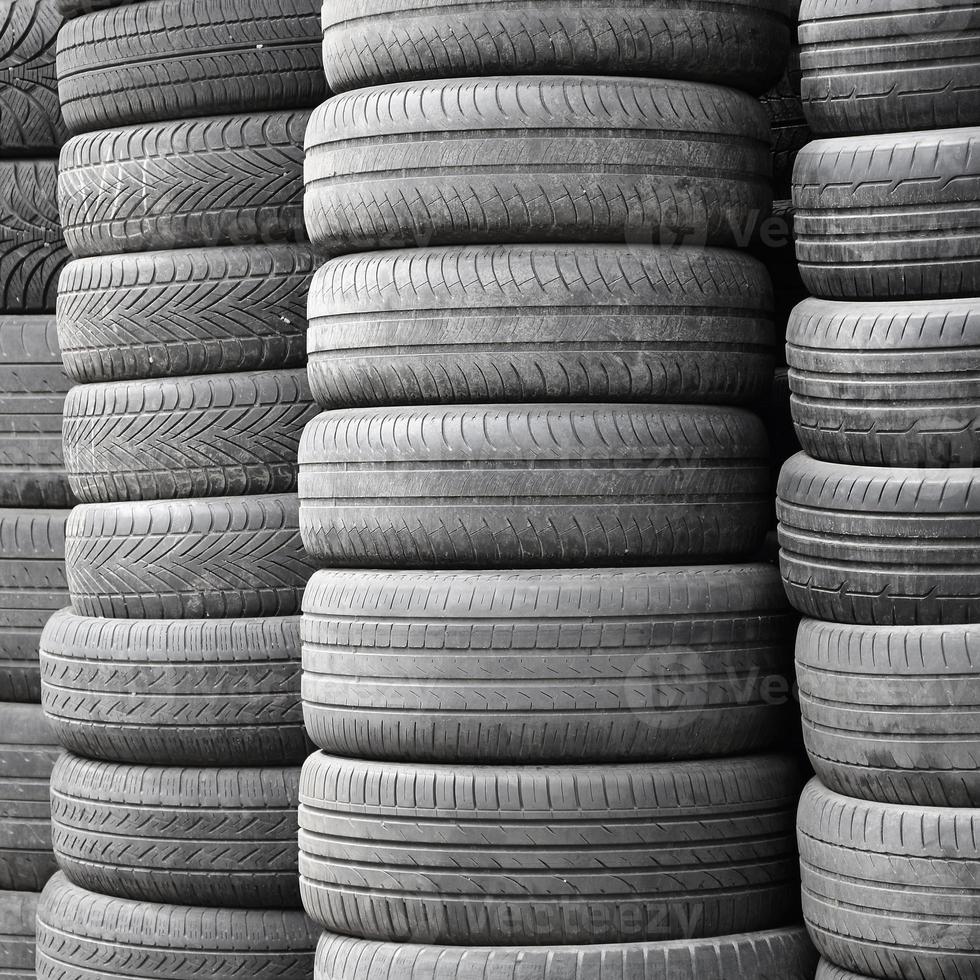 Old used tires stacked with high piles in secondary car parts shop garage photo