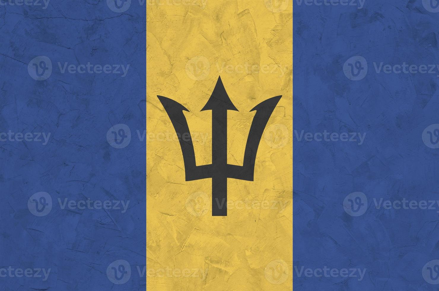 Barbados flag depicted in bright paint colors on old relief plastering wall. Textured banner on rough background photo