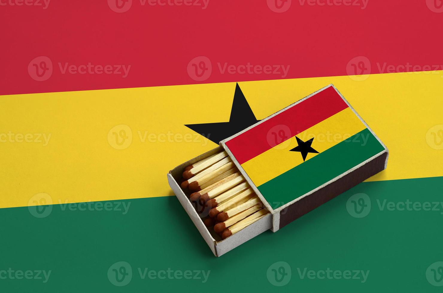 la bandera de ghana se muestra en una caja de fósforos abierta, que está llena de fósforos y se encuentra en una bandera grande foto