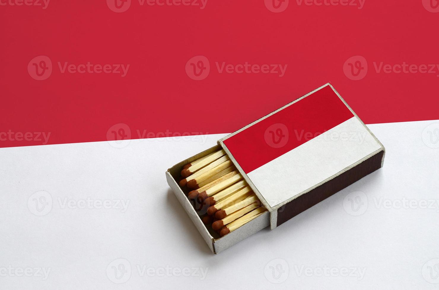 Indonesia flag is shown in an open matchbox, which is filled with matches and lies on a large flag photo