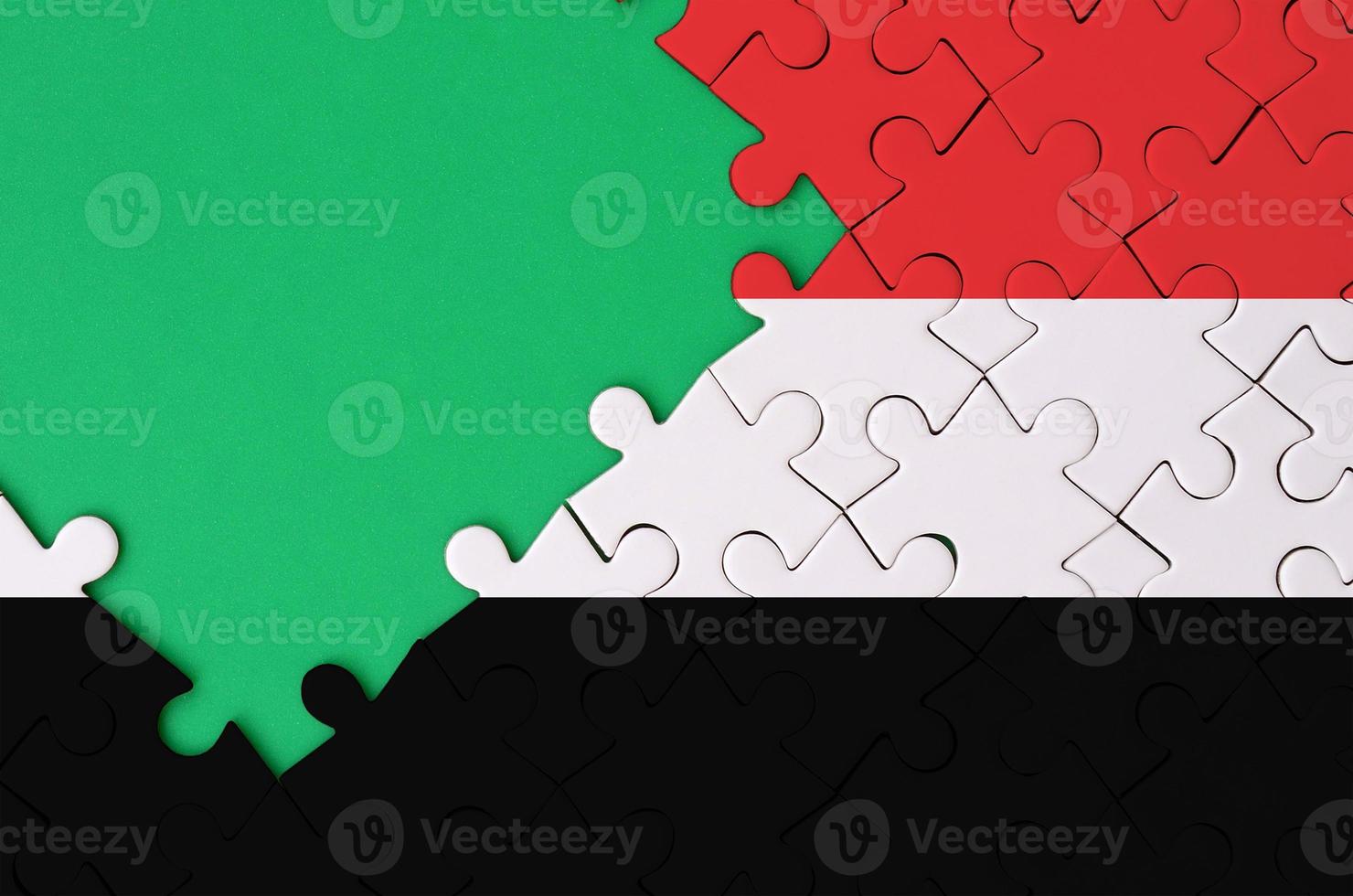 Yemen flag is depicted on a completed jigsaw puzzle with free green copy space on the left side photo