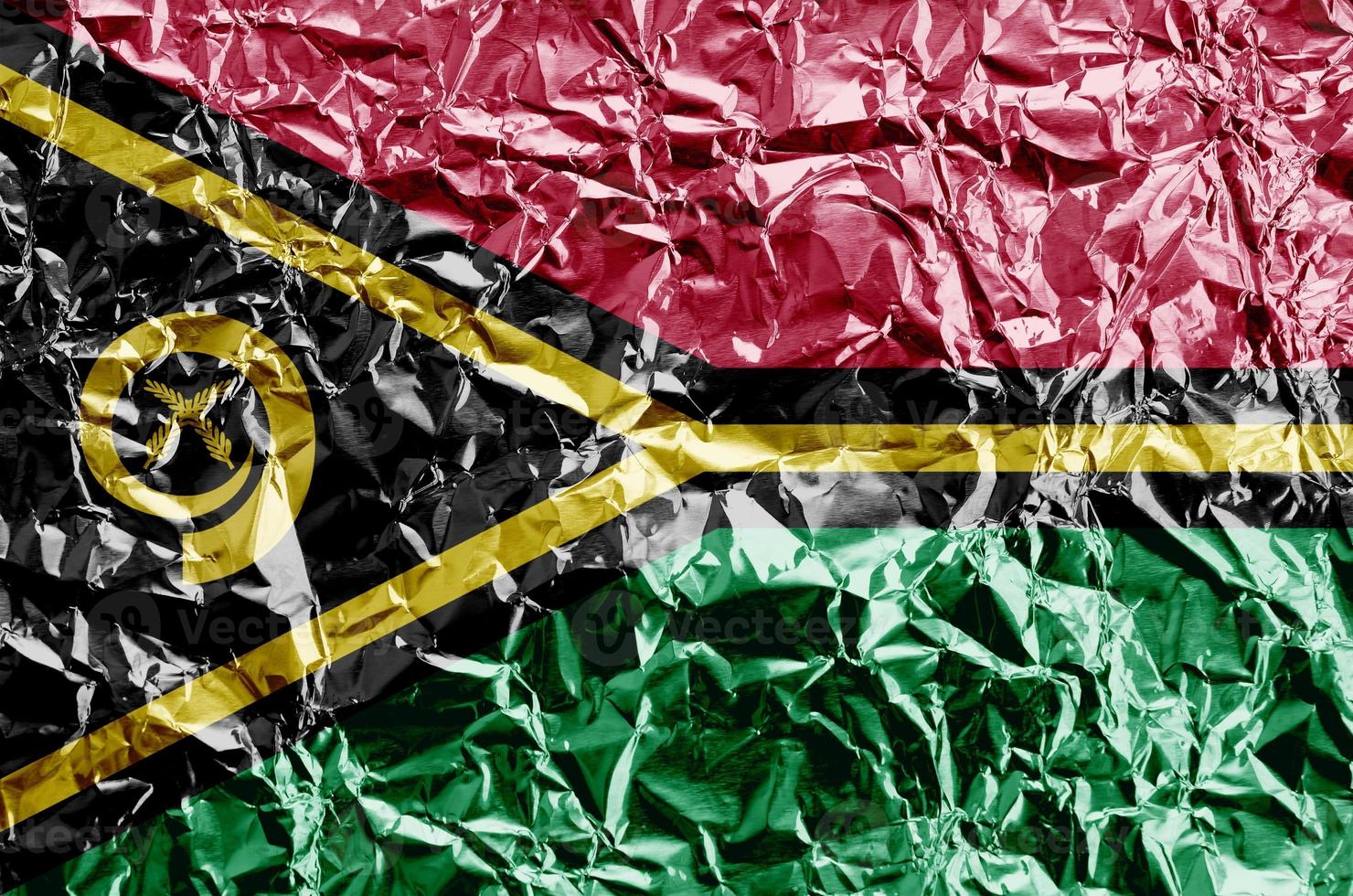 Vanuatu flag depicted in paint colors on shiny crumpled aluminium foil closeup. Textured banner on rough background photo