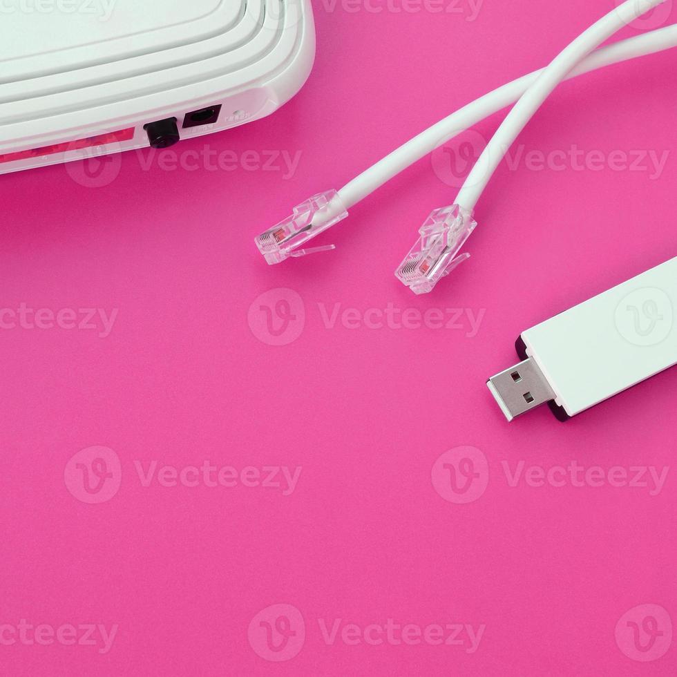 Internet router, portable USB wi-fi adapter and internet cable plugs lie on a bright pink background. Items required for internet photo