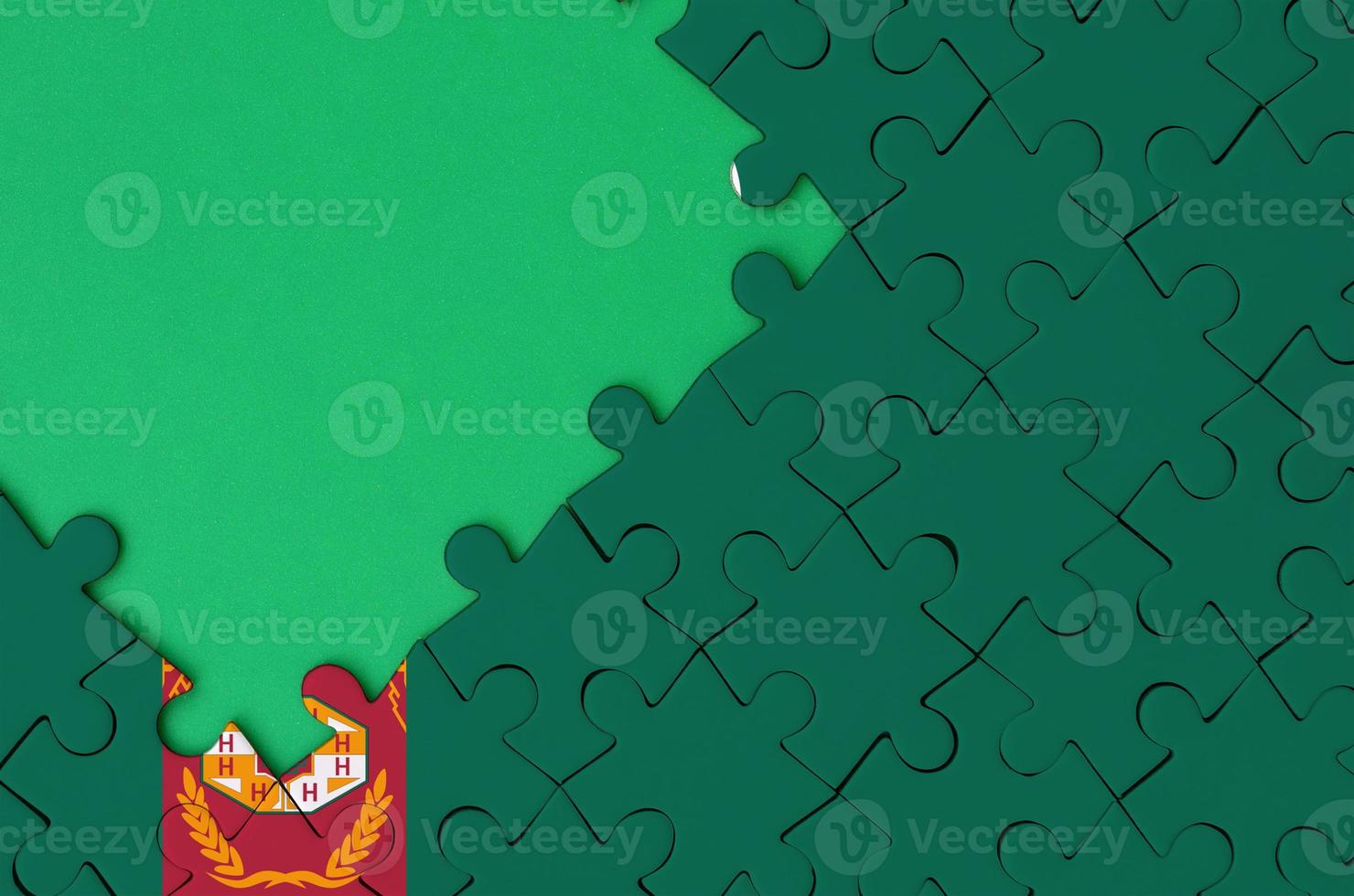 Turkmenistan flag is depicted on a completed jigsaw puzzle with free green copy space on the left side photo