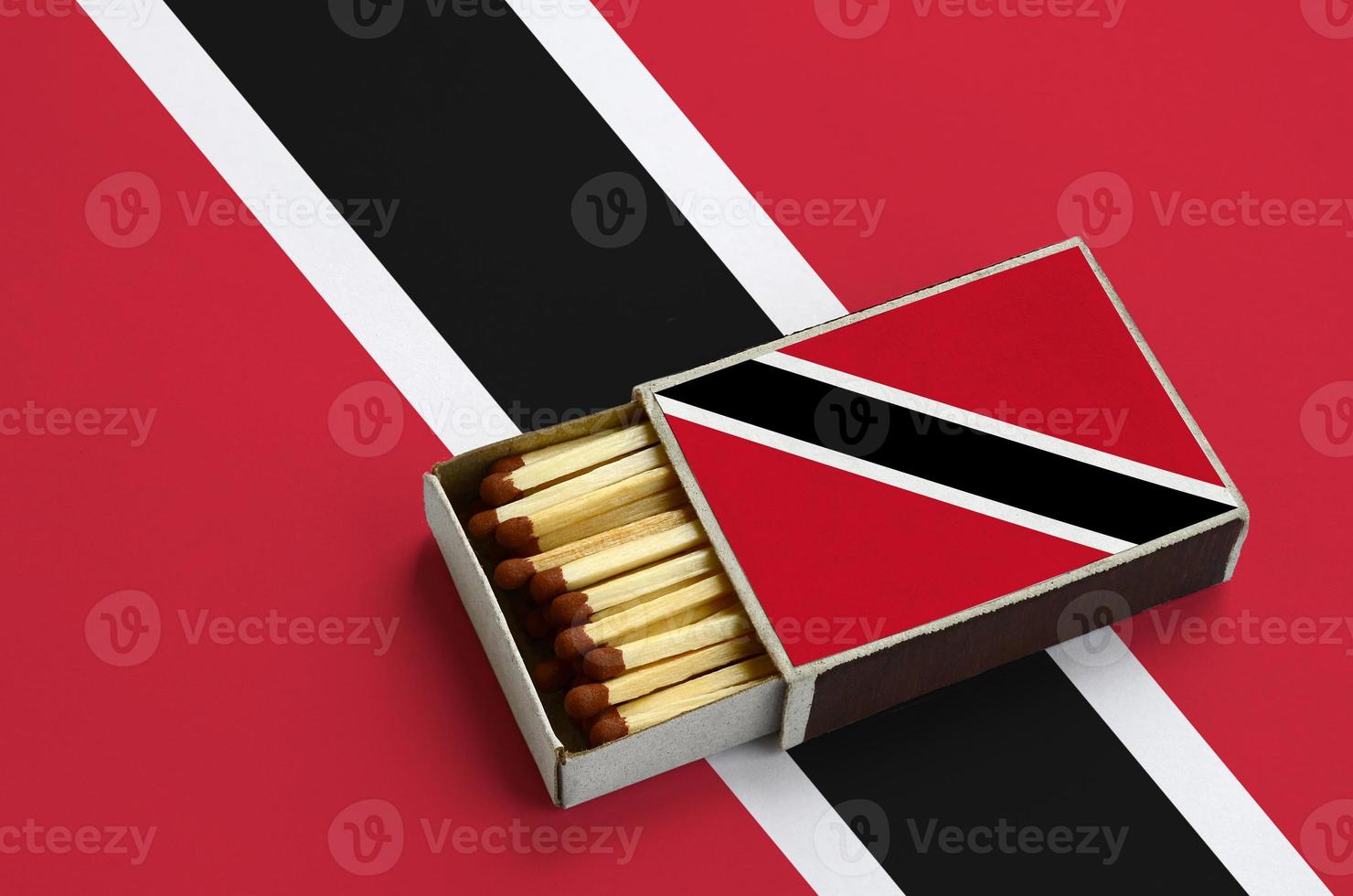 Trinidad and Tobago flag is shown in an open matchbox, which is filled with matches and lies on a large flag photo