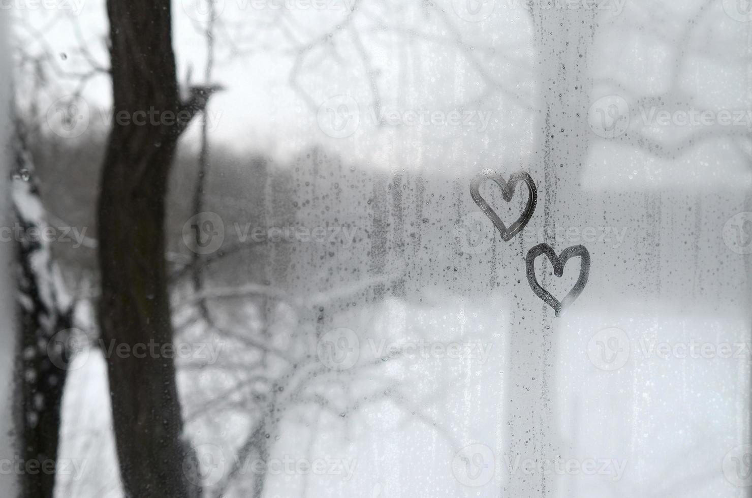 dos corazones pintados en un vidrio empañado en invierno foto