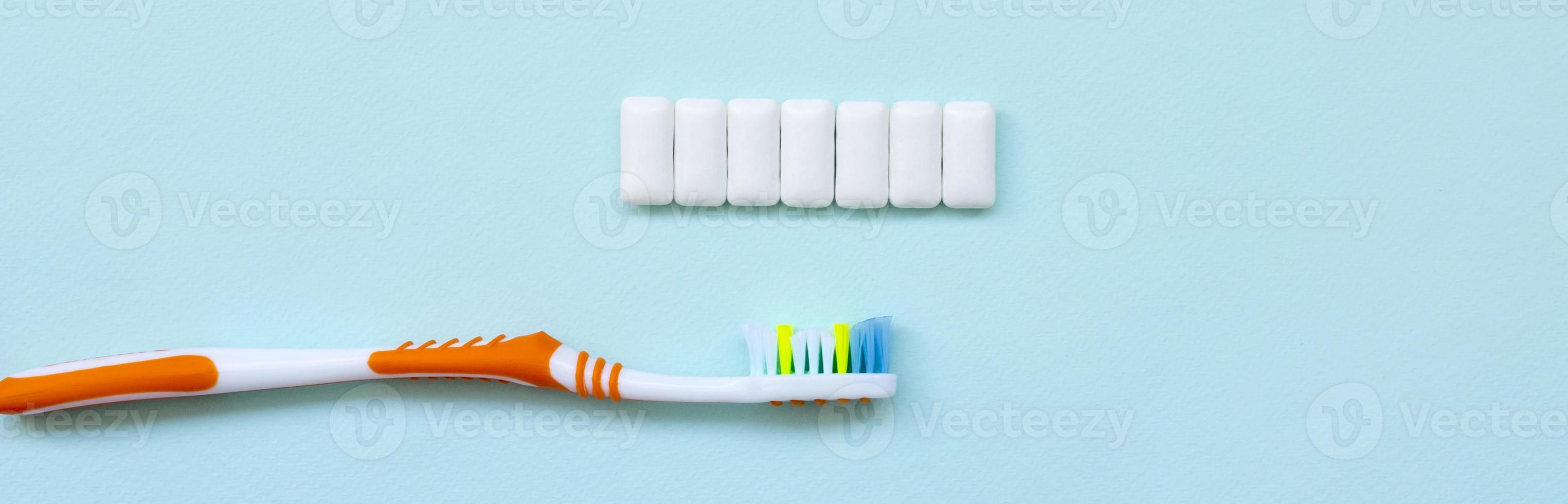 Toothbrush and chewing gums lie on a pastel blue background. Top view, flat lay. Minimal concept photo