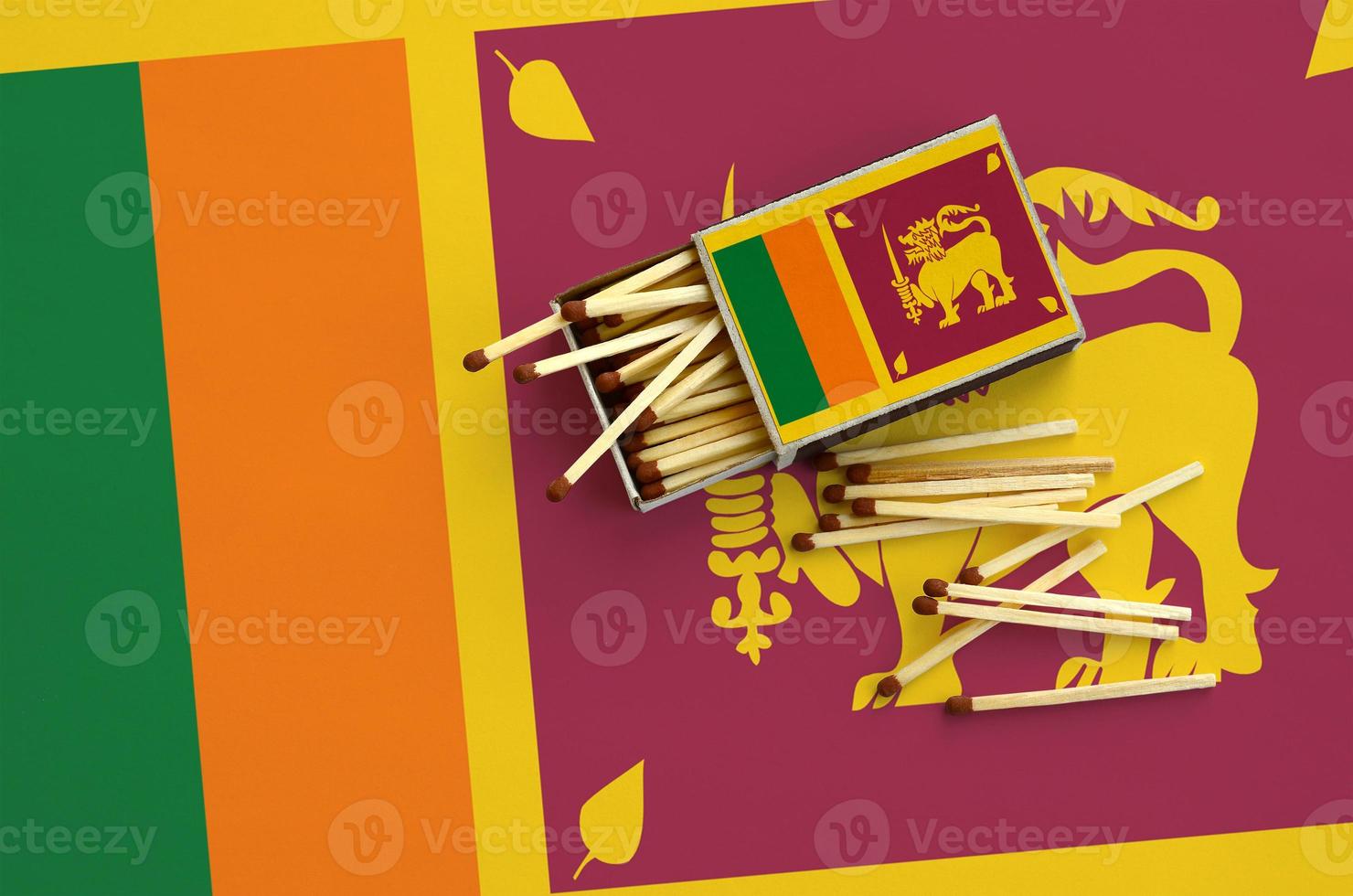 Sri Lanka flag is shown on an open matchbox, from which several matches fall and lies on a large flag photo