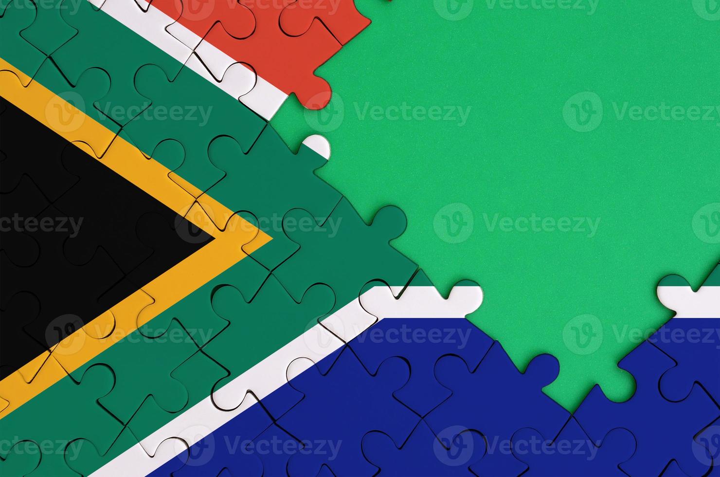 South Africa flag is depicted on a completed jigsaw puzzle with free green copy space on the right side photo