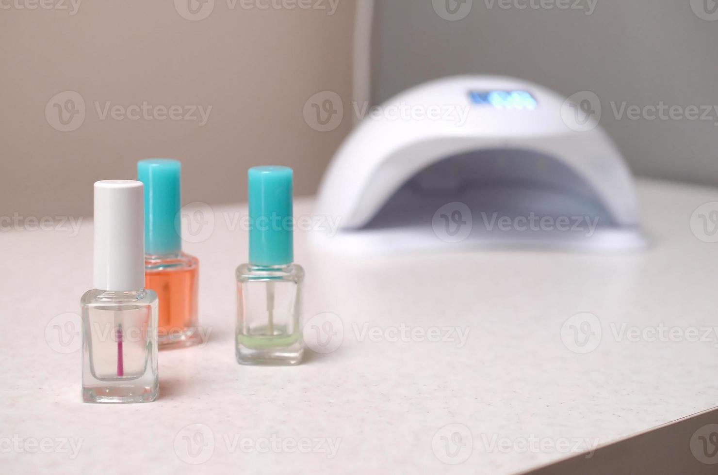 luces de lámpara de diodo uv para uñas y juego de esmalte de uñas cosmético para manicura y pedicura sobre fondo de mesa blanco foto