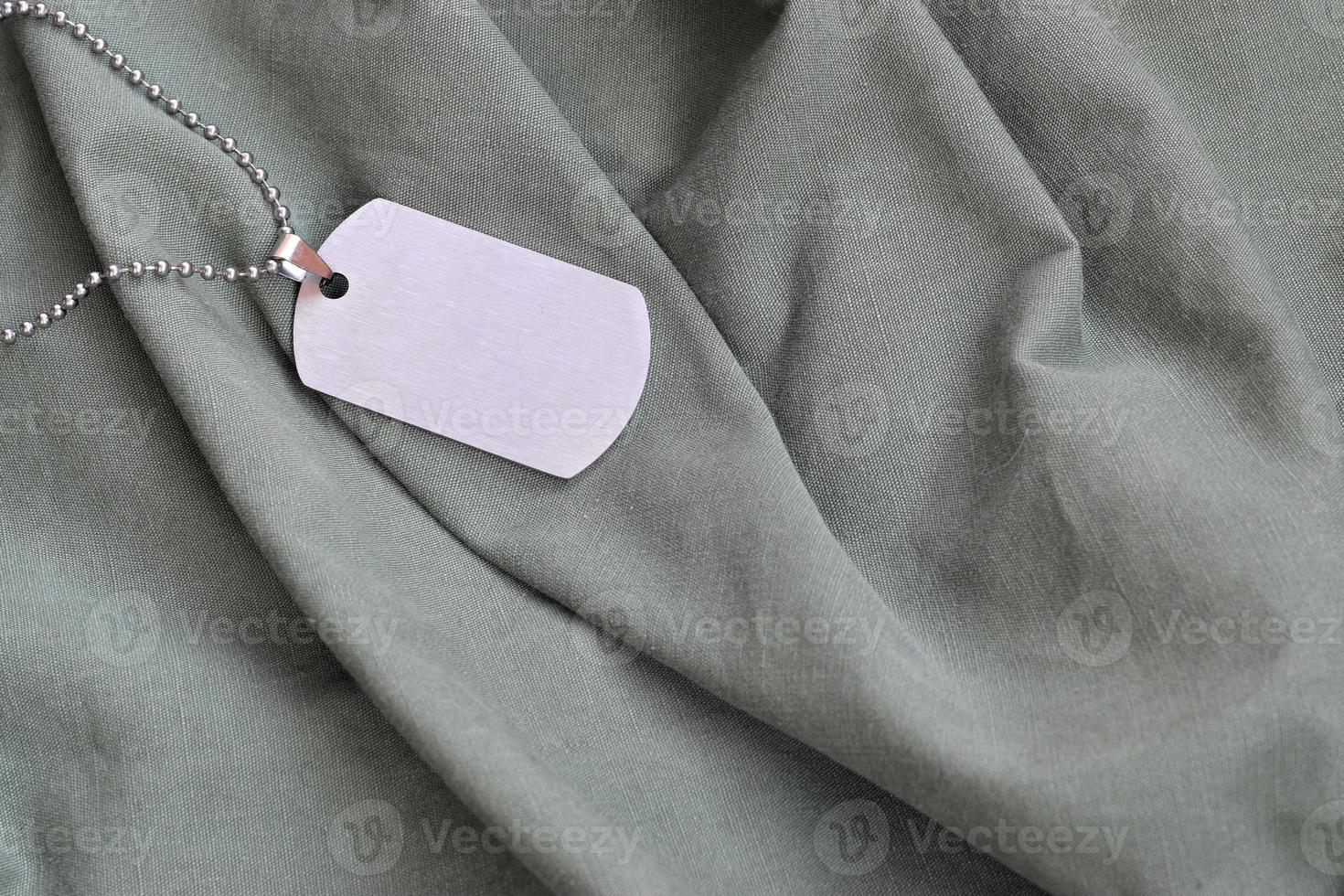 Silvery military beads with dog tag on dark green private fatigue uniform photo