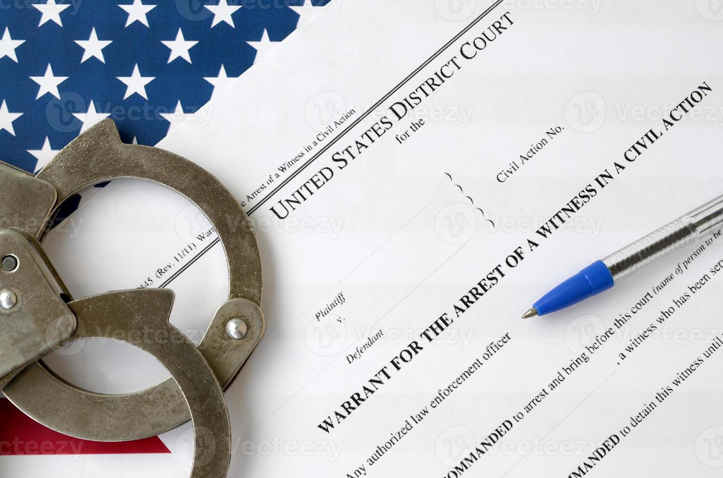 District court warrant for the arrest of a witness in a civil action papers with handcuffs and blue pen on United States flag. Permission to witness arrest photo