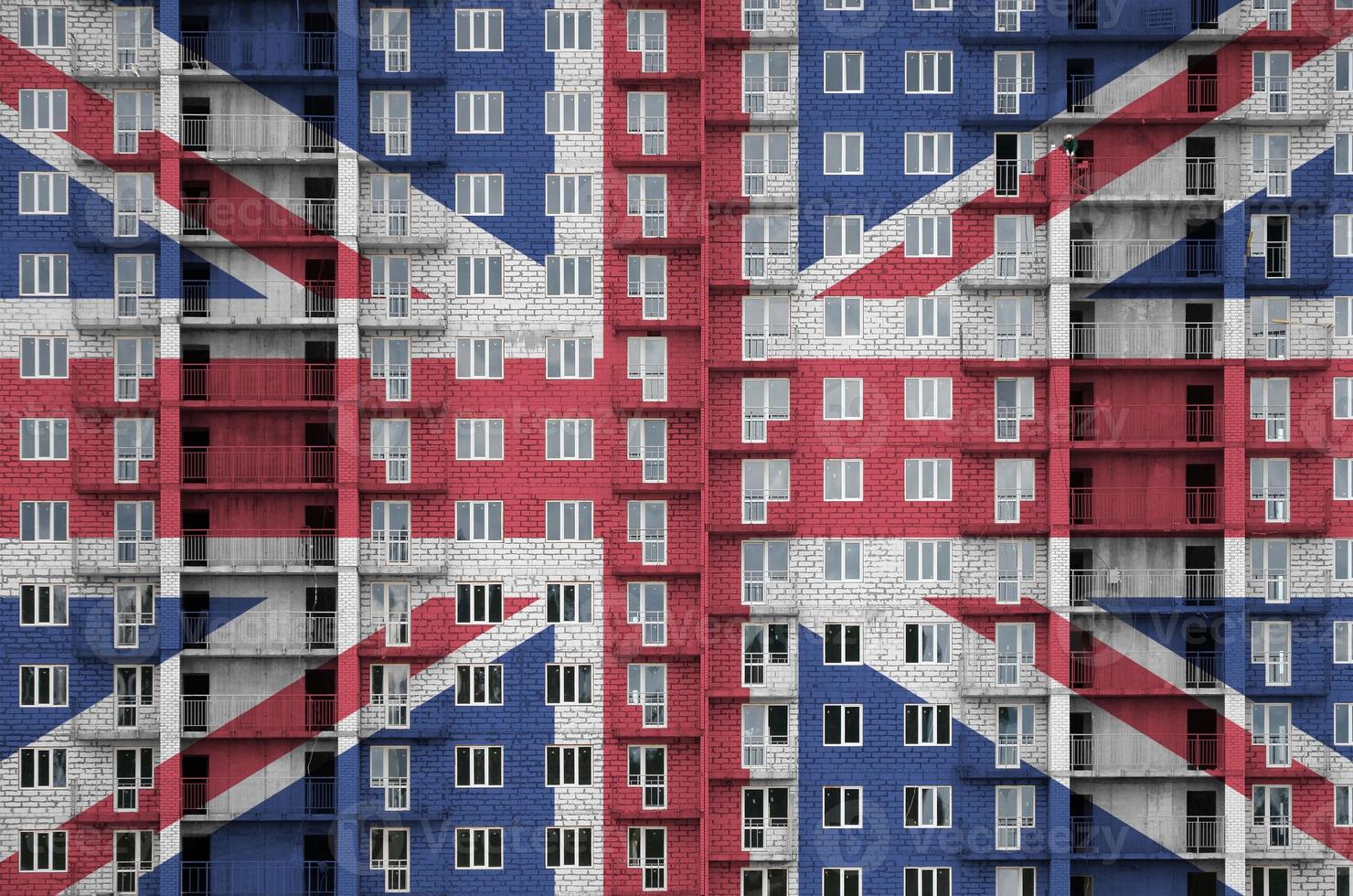Great britain flag depicted in paint colors on multi-storey residental building under construction. Textured banner on brick wall background photo