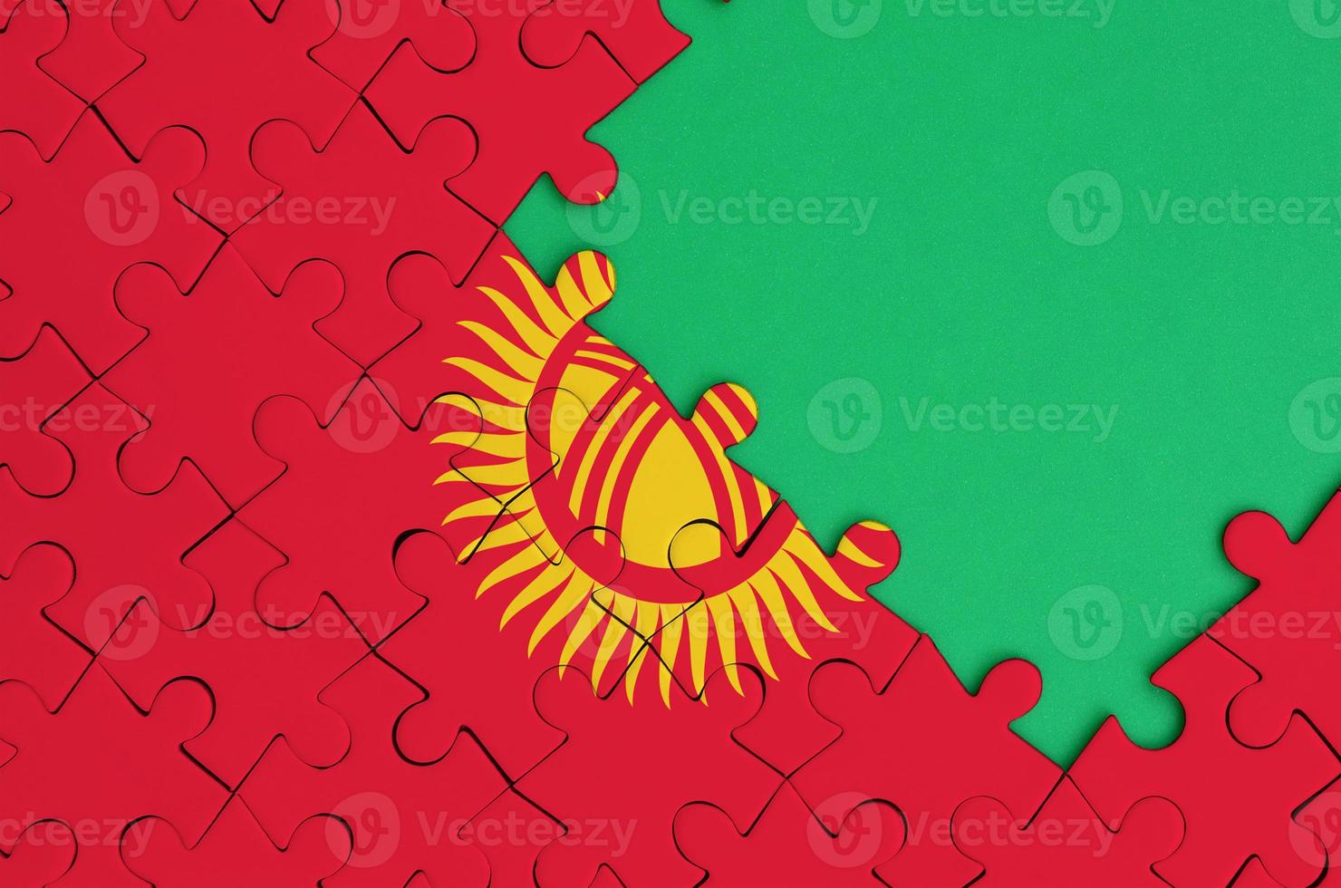 Kyrgyzstan flag is depicted on a completed jigsaw puzzle with free green copy space on the right side photo