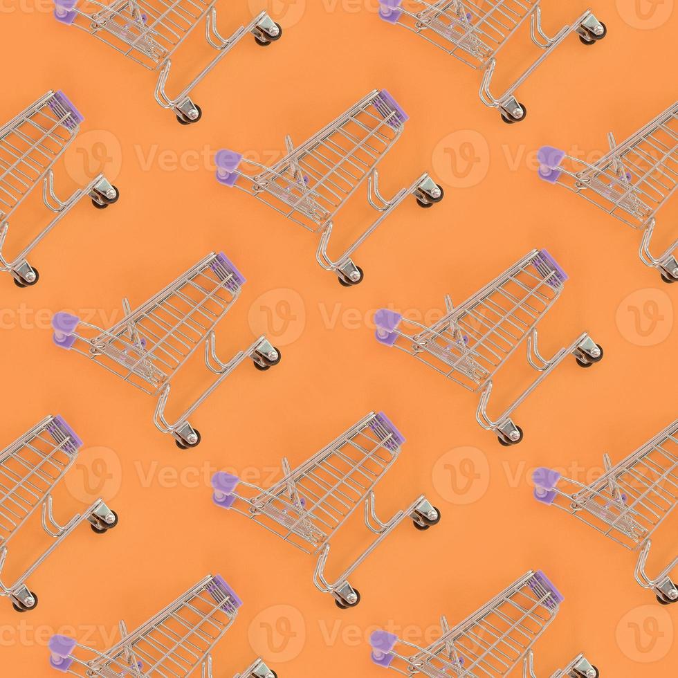 Shopping addiction, shopping lover or shopaholic concept. Many small empty shopping carts perform a pattern on a pastel colored paper background. Flat lay composition, top view photo