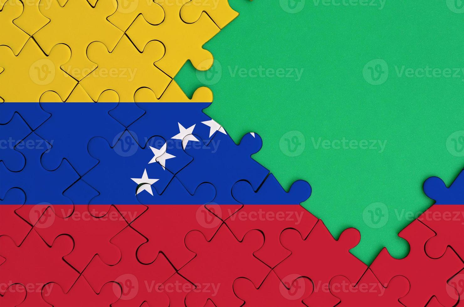 Venezuela flag is depicted on a completed jigsaw puzzle with free green copy space on the right side photo