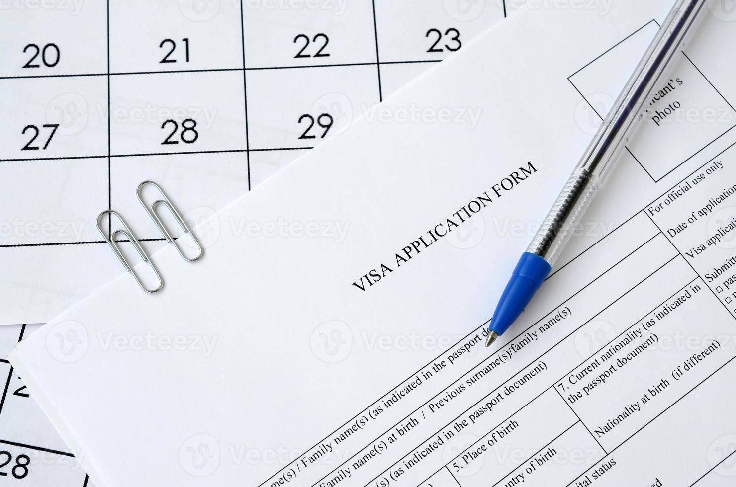 formulario típico de solicitud de visa y bolígrafo azul en la página del calendario de papel foto