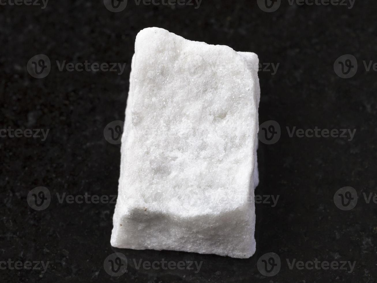 piece of rough white marble stone on dark photo