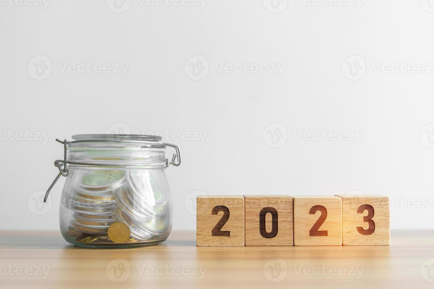 Bloque del año 2023 con tarro de dinero, presupuesto, impuestos, inversiones, finanzas, ahorros y conceptos de resolución de año nuevo foto