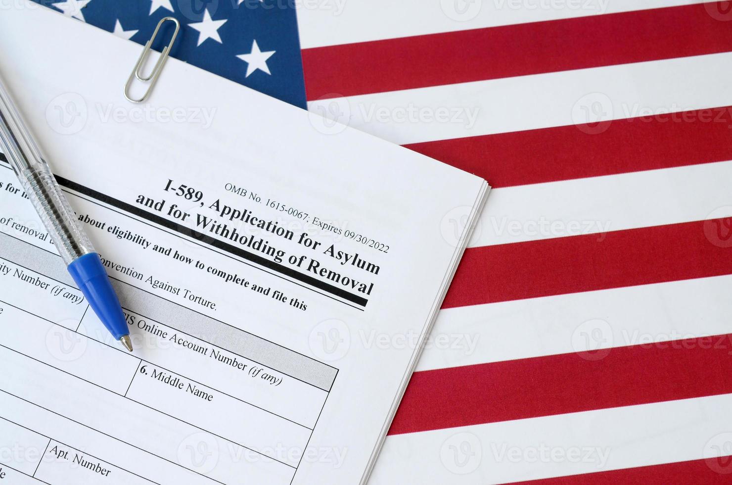 I-589 Application for asylum and for withholding of removal blank form lies on United States flag with blue pen from Department of Homeland Security photo