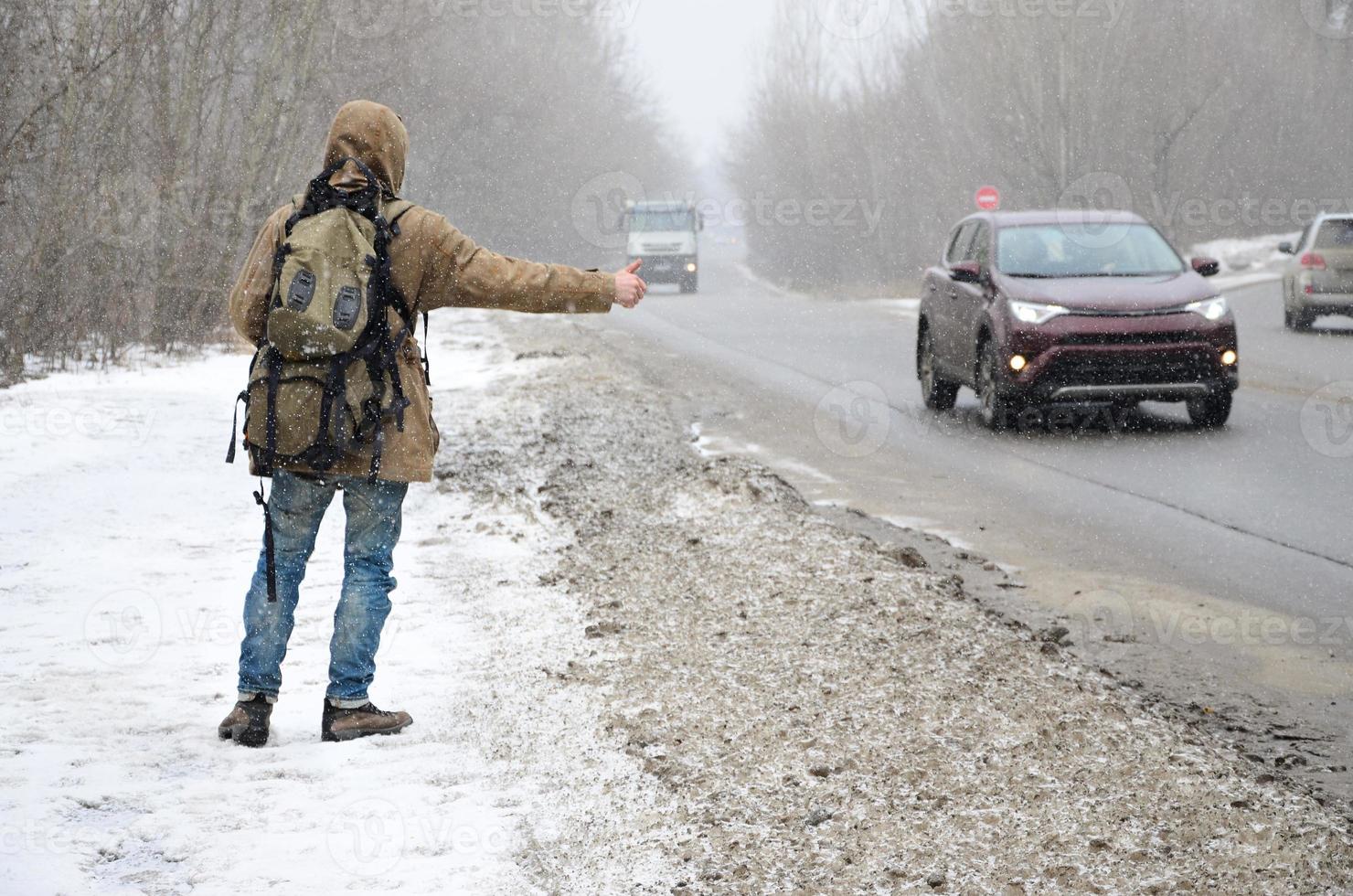 A man with a large backpack showing thumbs up for hitchhiking du photo