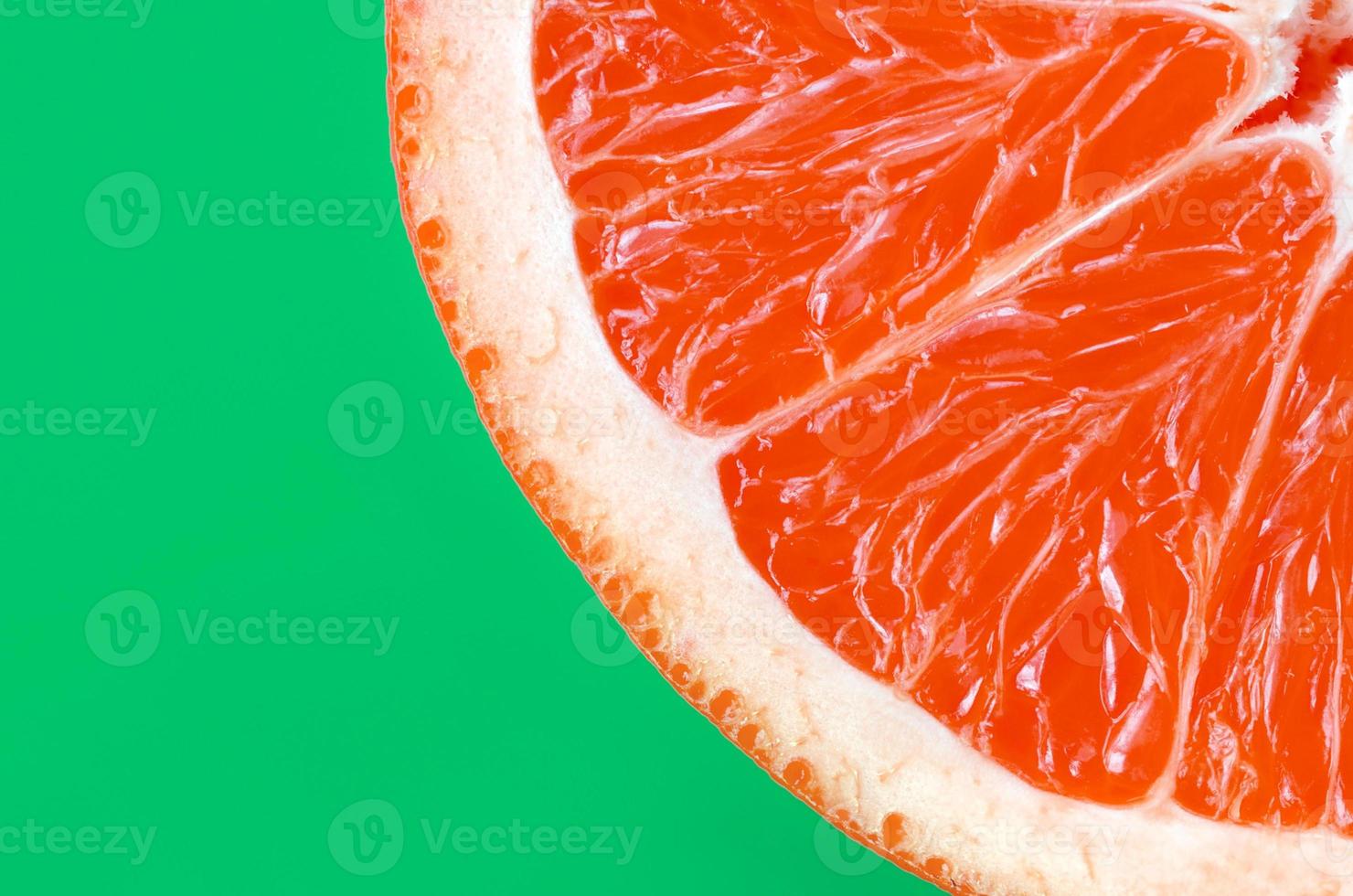 Top view of an one grapefruit slice on bright background in green color. A saturated citrus texture image photo