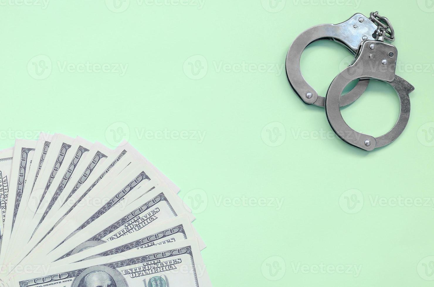 Police handcuffs and hundreds of us dollars lie on a lime background photo