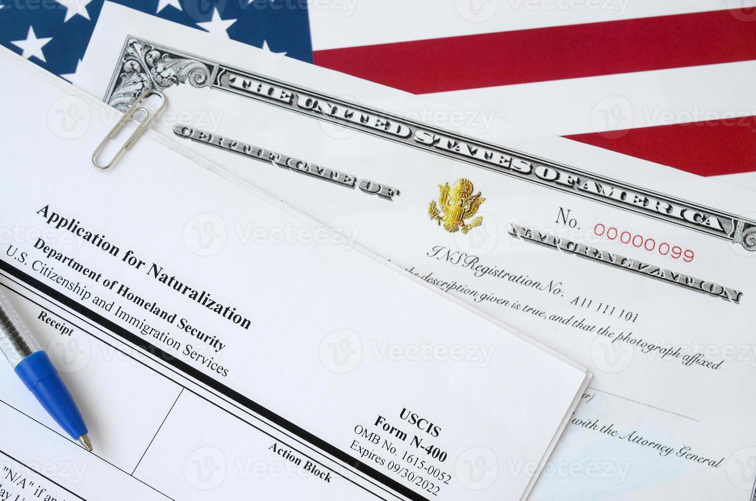 N-400 Application for Naturalization and Certificate of naturalization lies on United States flag with blue pen from Department of Homeland Security photo
