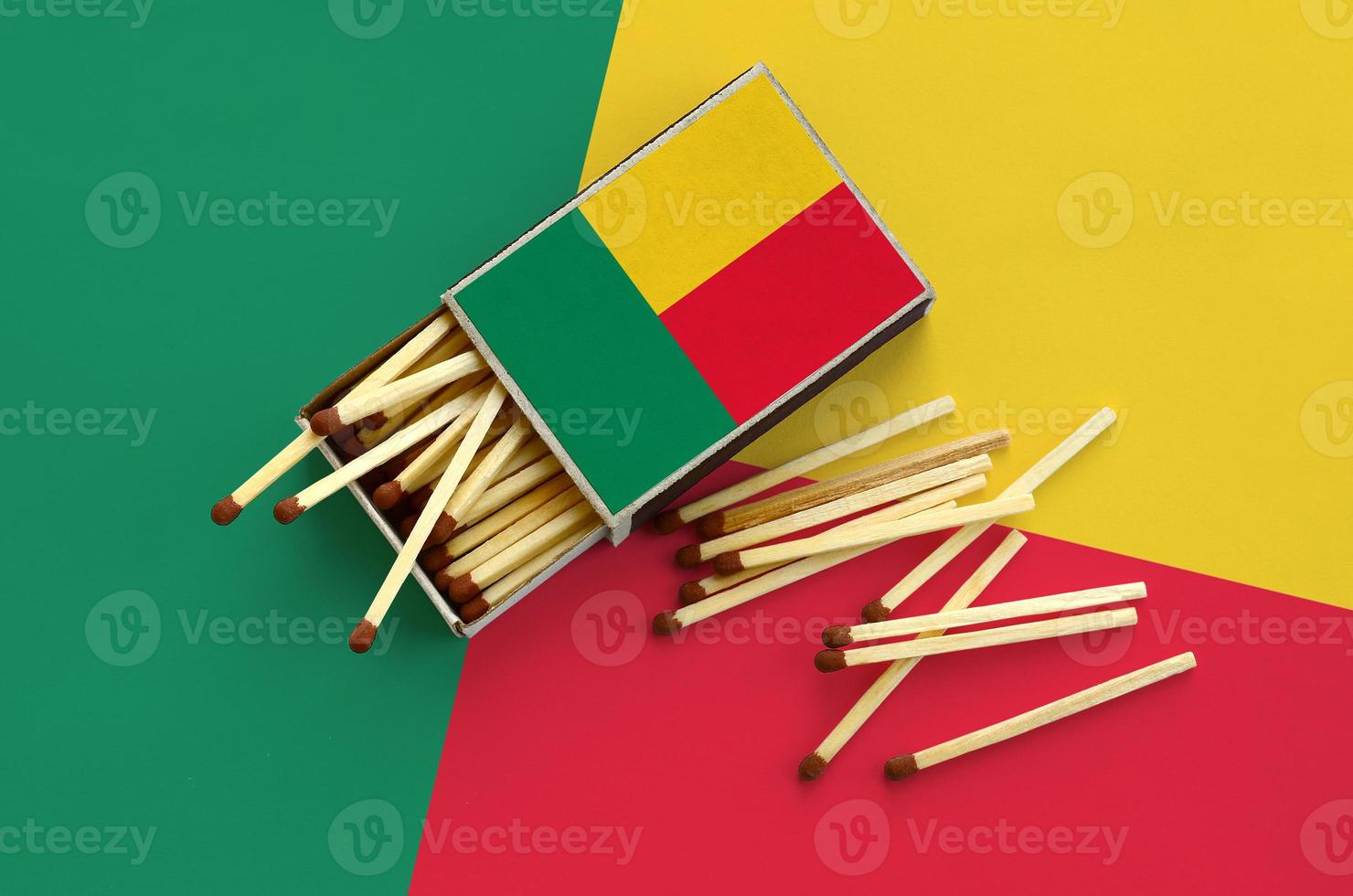 Benin flag is shown on an open matchbox, from which several matches fall and lies on a large flag photo