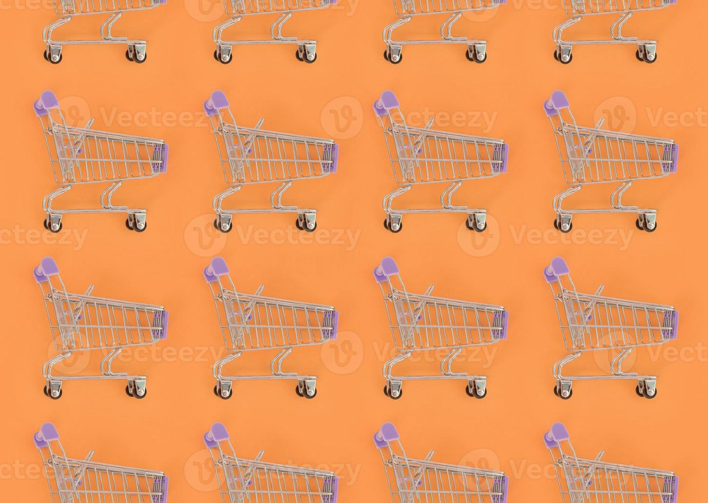 Shopping addiction, shopping lover or shopaholic concept. Many small empty shopping carts perform a pattern on a pastel colored paper background. Flat lay composition, top view photo