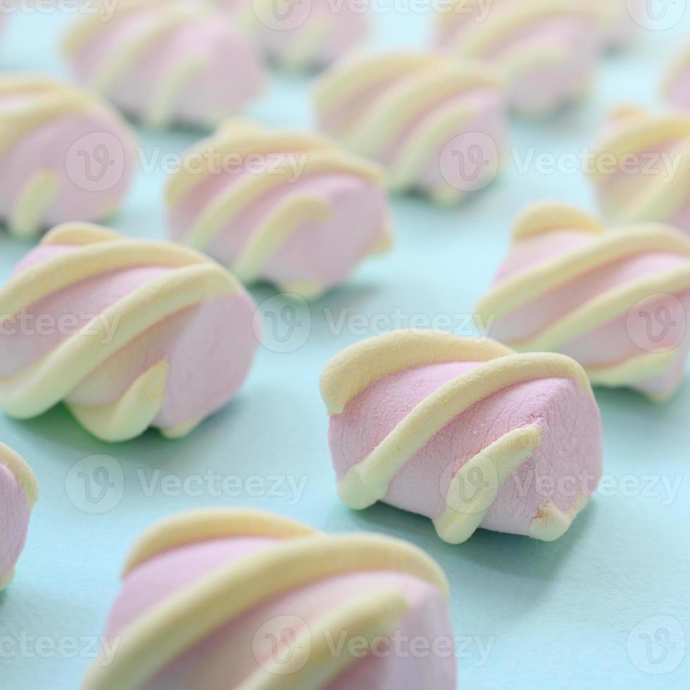 Colorful marshmallow laid out on blue paper background. pastel creative textured pattern. Perspective macro shot photo