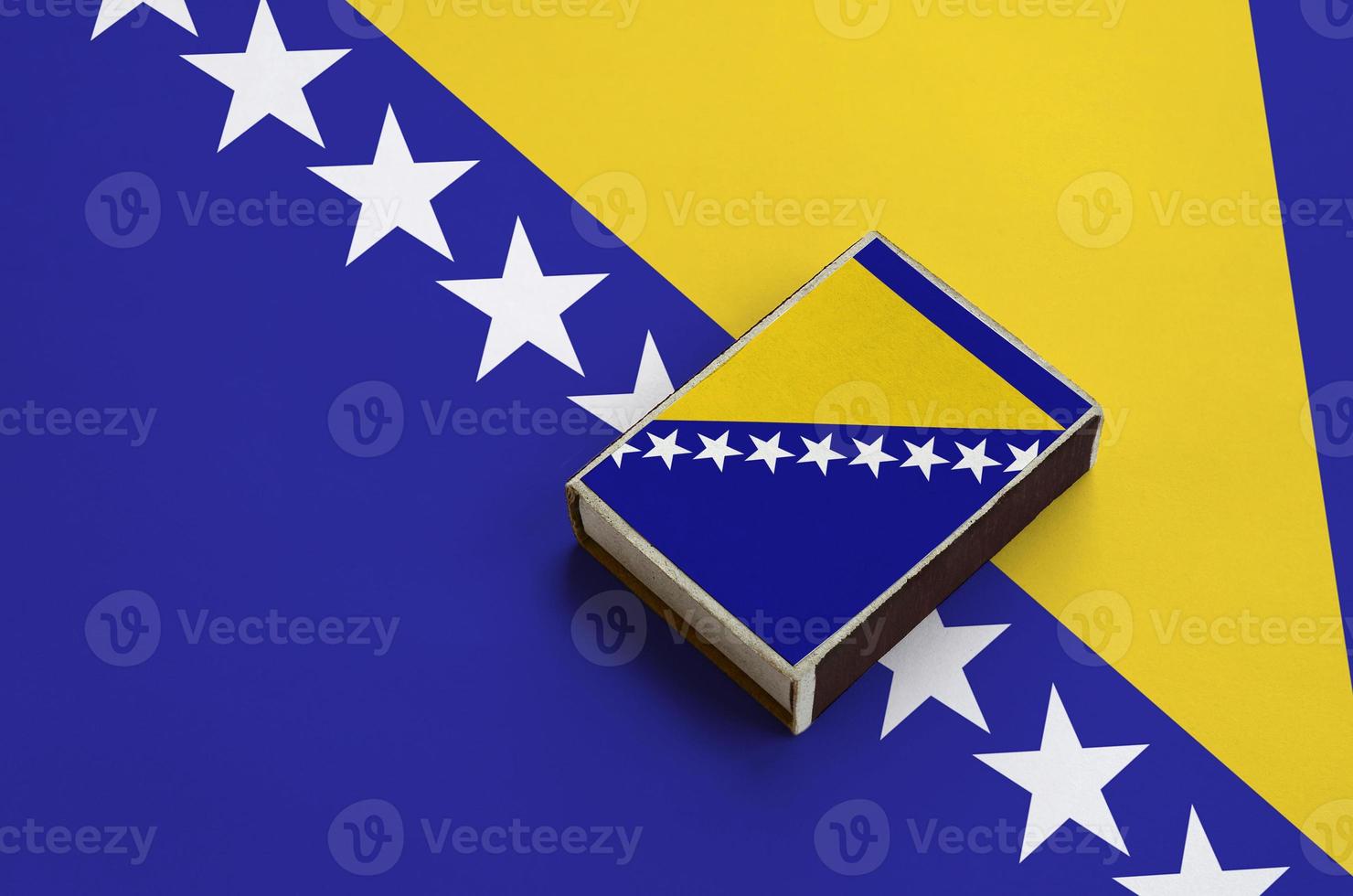 Bosnia and Herzegovina flag is pictured on a matchbox that lies on a large flag photo