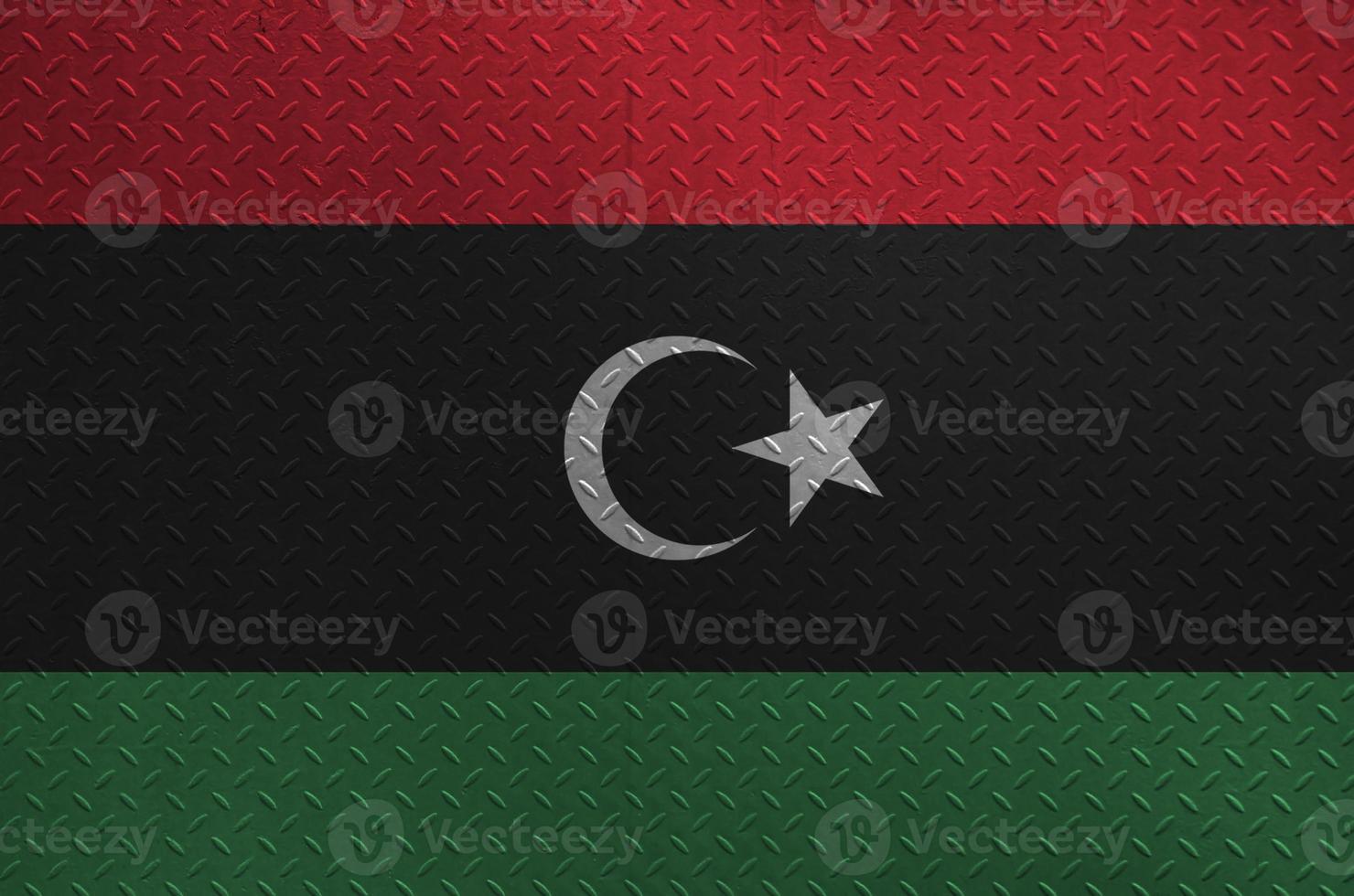 Libya flag depicted in paint colors on old brushed metal plate or wall closeup. Textured banner on rough background photo