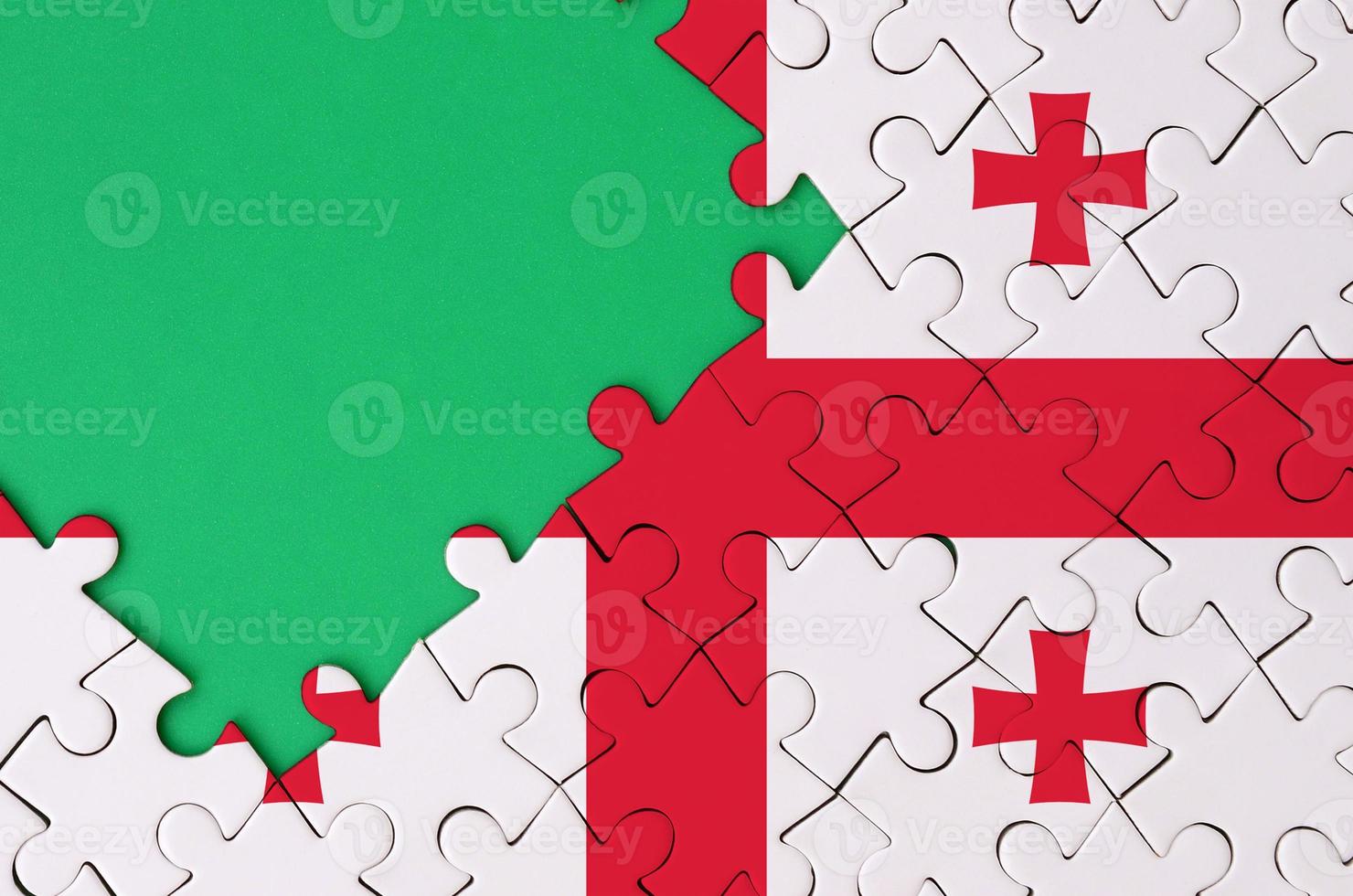 Georgia flag is depicted on a completed jigsaw puzzle with free green copy space on the left side photo