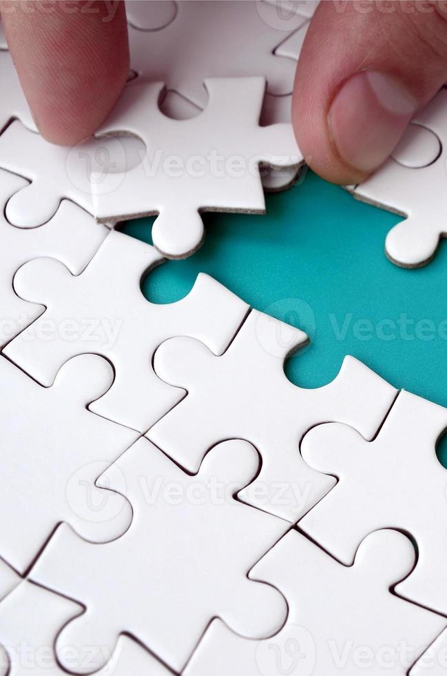 The human hand paves the way to the surface of the jigsaw puzzle, forming a blue space. The concept of overcoming the difficulties on the way to success photo