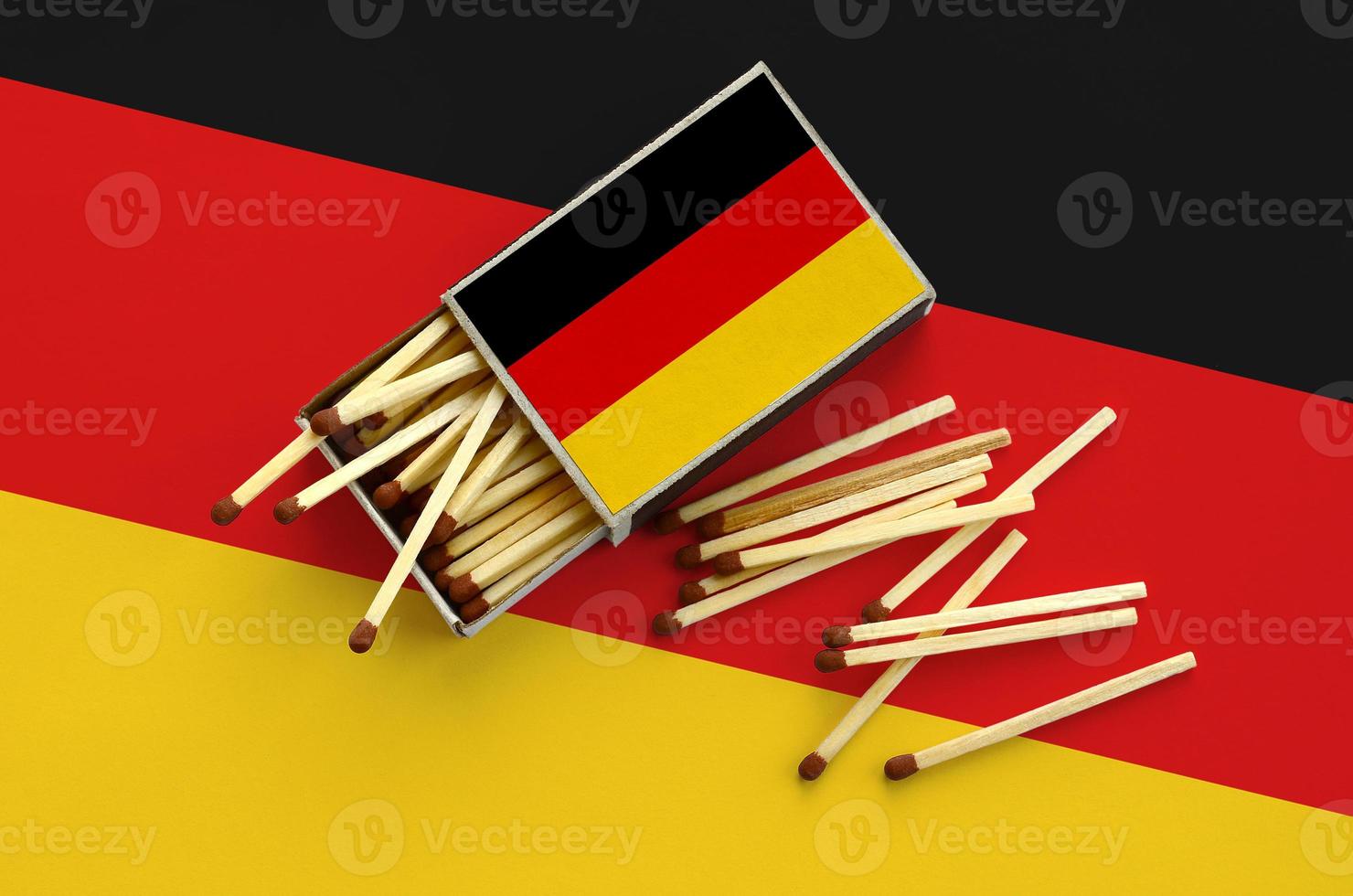 Germany flag is shown on an open matchbox, from which several matches fall and lies on a large flag photo