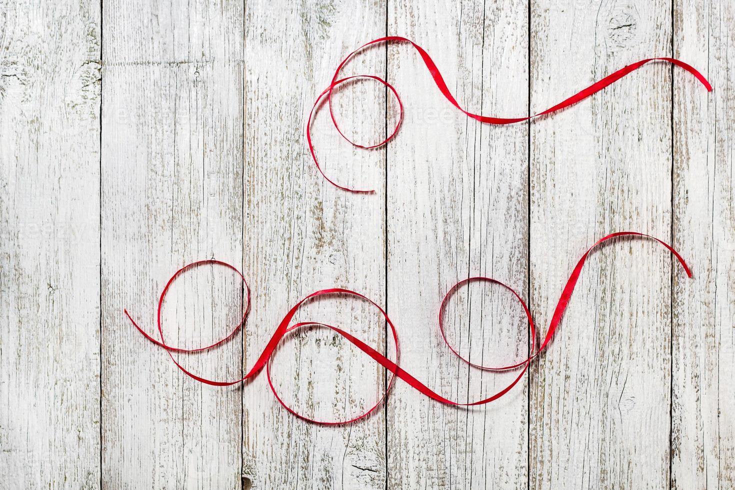 Red ribbons on the white wooden background photo