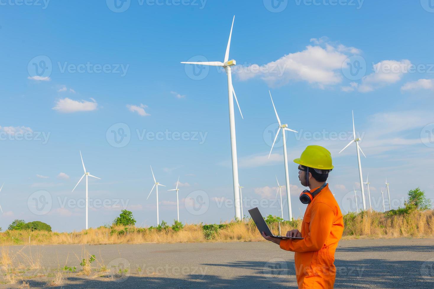 Silhouette of man engineer working and holding the report at wind turbine farm Power Generator Station on mountain,Thailand people photo